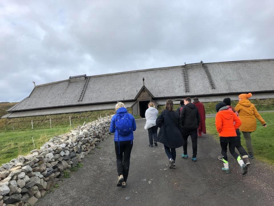 ca 10 personer går mot inngangen på langhuset på vikingmussees på Borg i Lofoten - Klikk for stort bilde