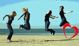 På bildet ser vi fire kvinner som tar sats og hopper. De står på en strand, og i bakgrunnen ser vi havet. Det er plassert et hjerte til høyre i bildet. - Klikk for stort bilde